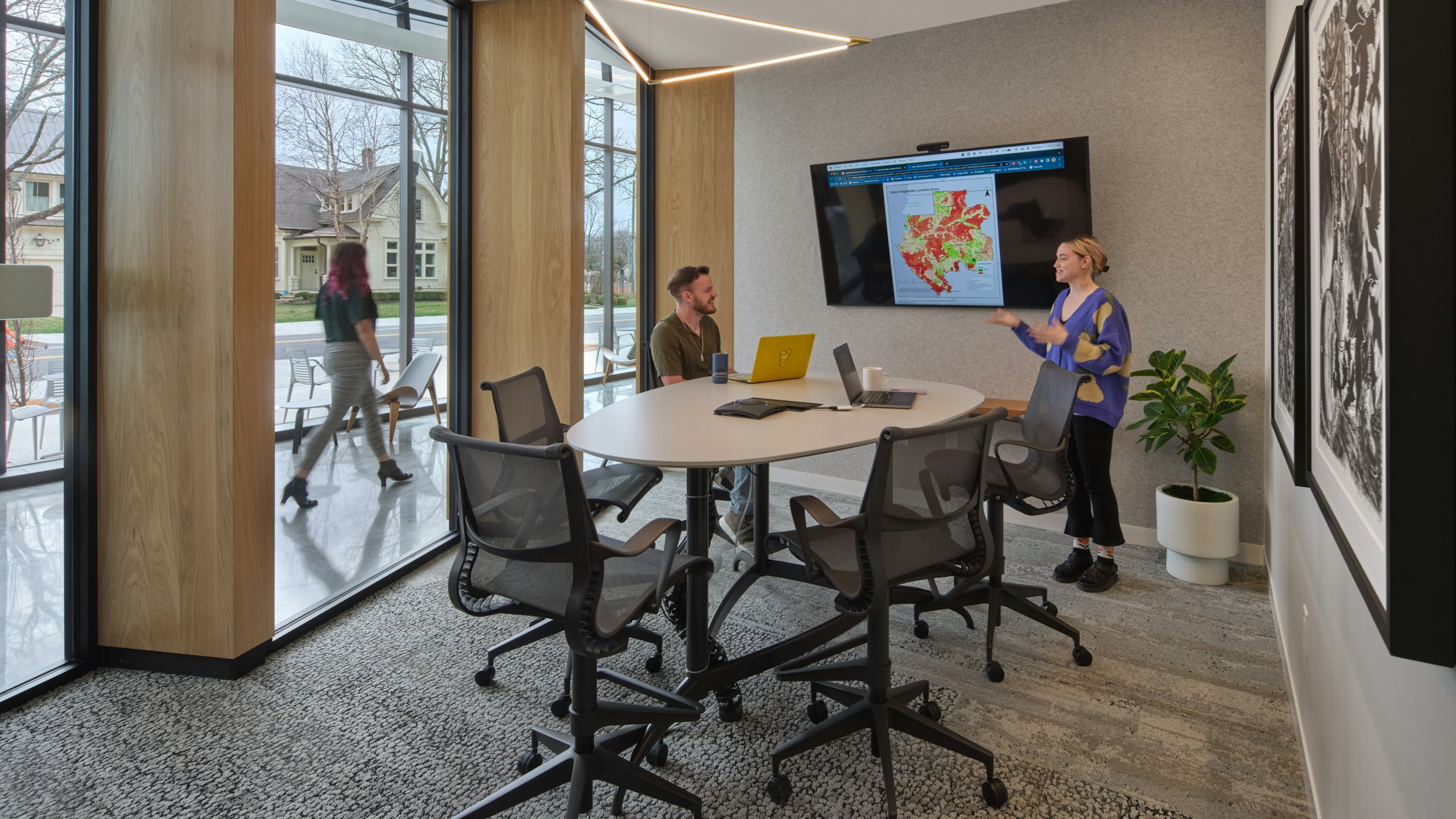 Two individuals having a discussion in a meeting space furnished with Herman Miller Setu Chairs