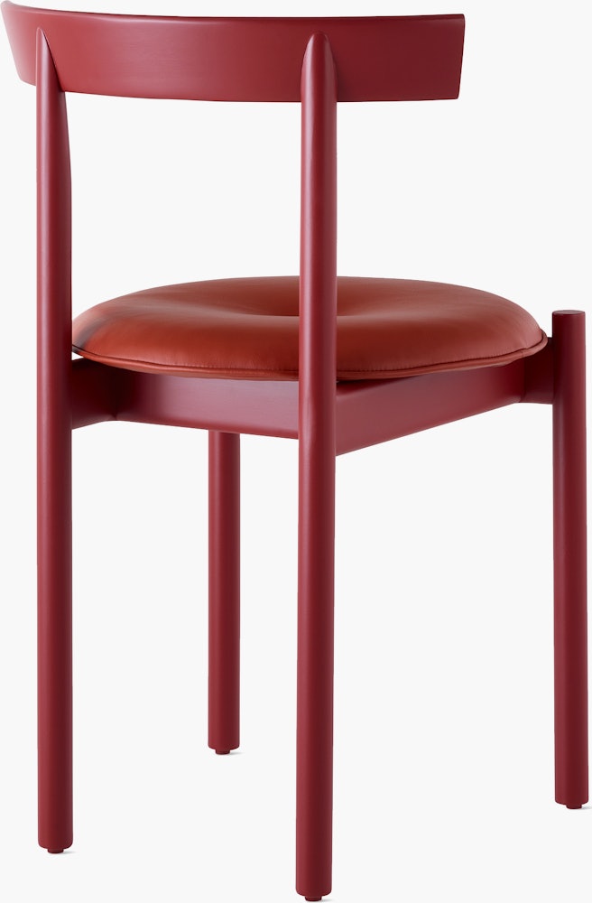 A red Comma Chair with a seat pad, viewed from the back at an angle.