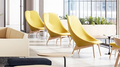 A group of yellow HAY Uchiwa Lounge Chairs in front of large floor-to-ceiling windows used in a community café setting to reduce social isolation and enhance belonging