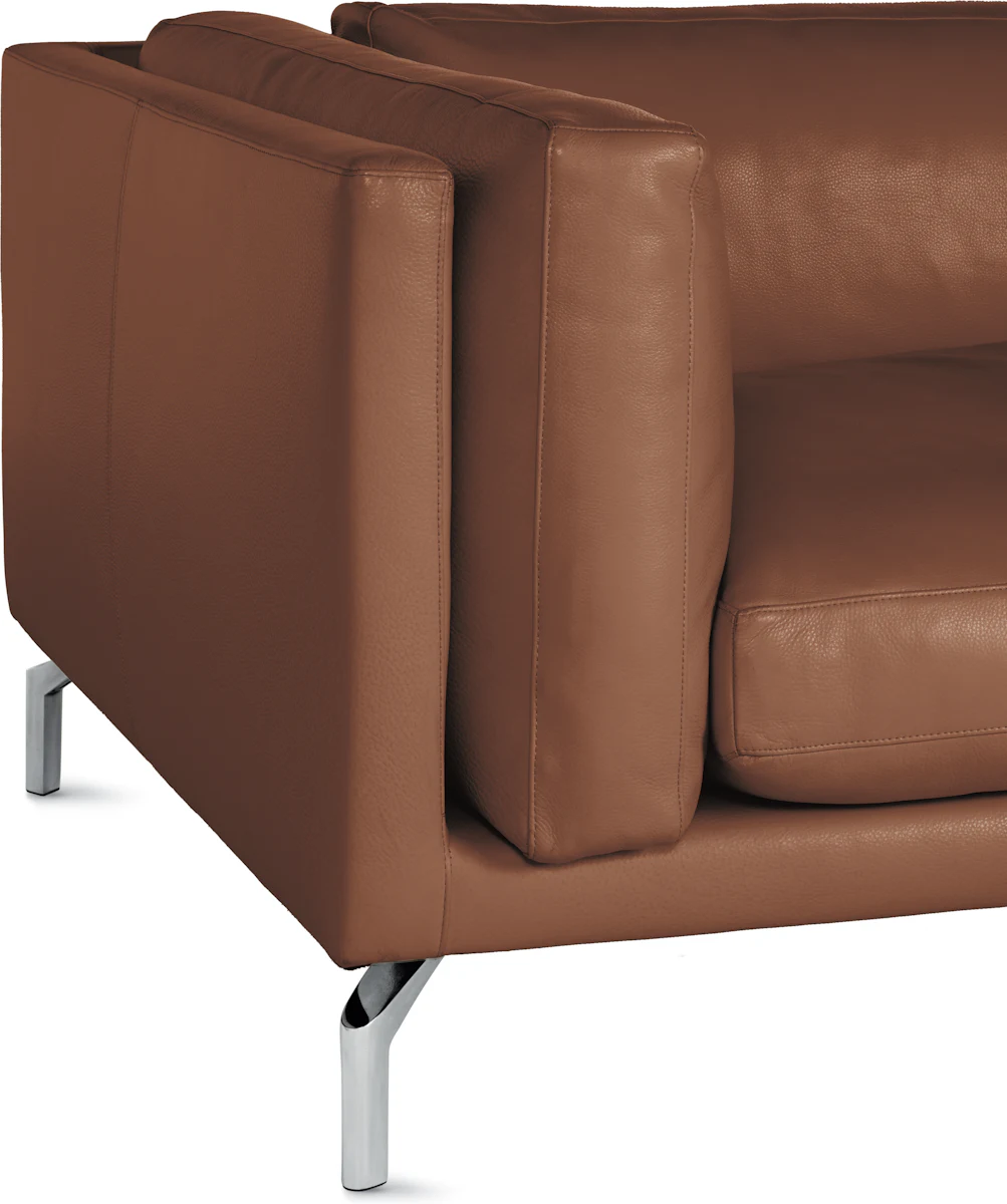Close-up of a brown leather armrest and seat of a modern sofa with metal legs