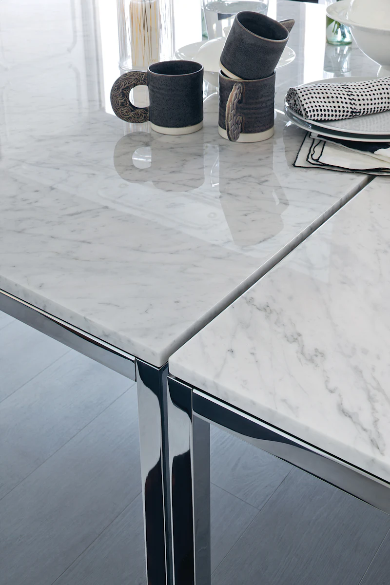 Close-up of marble tabletop with mugs, cups, and napkins reflecting on glossy surface