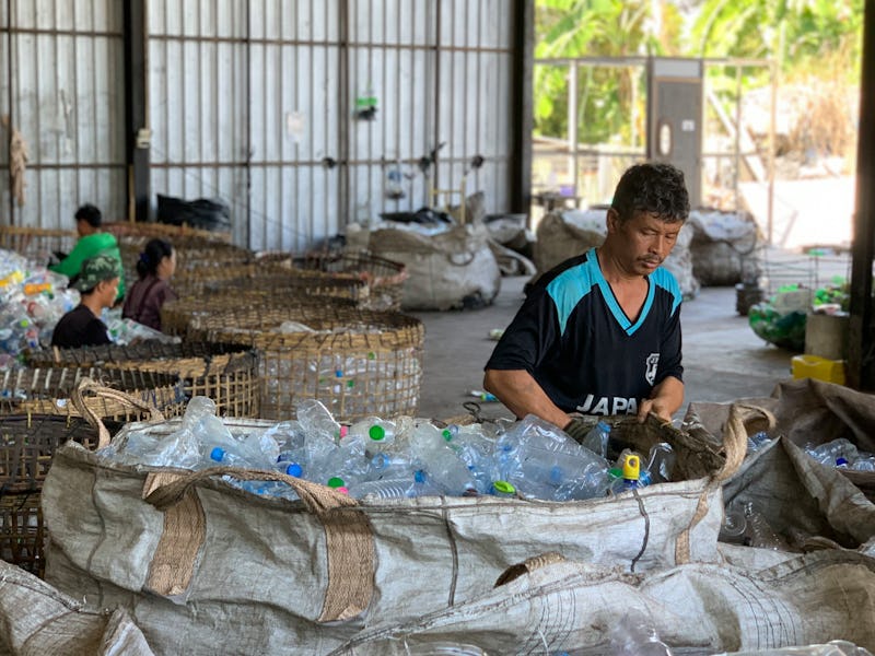 A man sorting plastic bottles in a warehouse. 